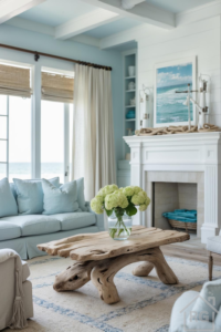 Bright coastal style living room featuring a driftwood coffee table, pale blue sofa, and white fireplace with ocean artwork.