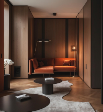 A modern apartment lounge featuring warm wood paneling, a sleek orange sofa, and minimalist furniture.