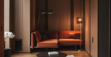 A modern apartment lounge featuring warm wood paneling, a sleek orange sofa, and minimalist furniture.