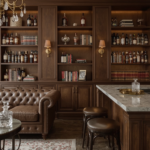 Classic-modern home whiskey lounge with dark wood shelves, tufted leather sofa, marble bar, and warm lighting.
